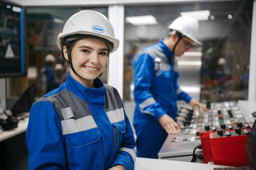 Confident female engineer smiling in an industrial control room. Teamwork and safety in operations.